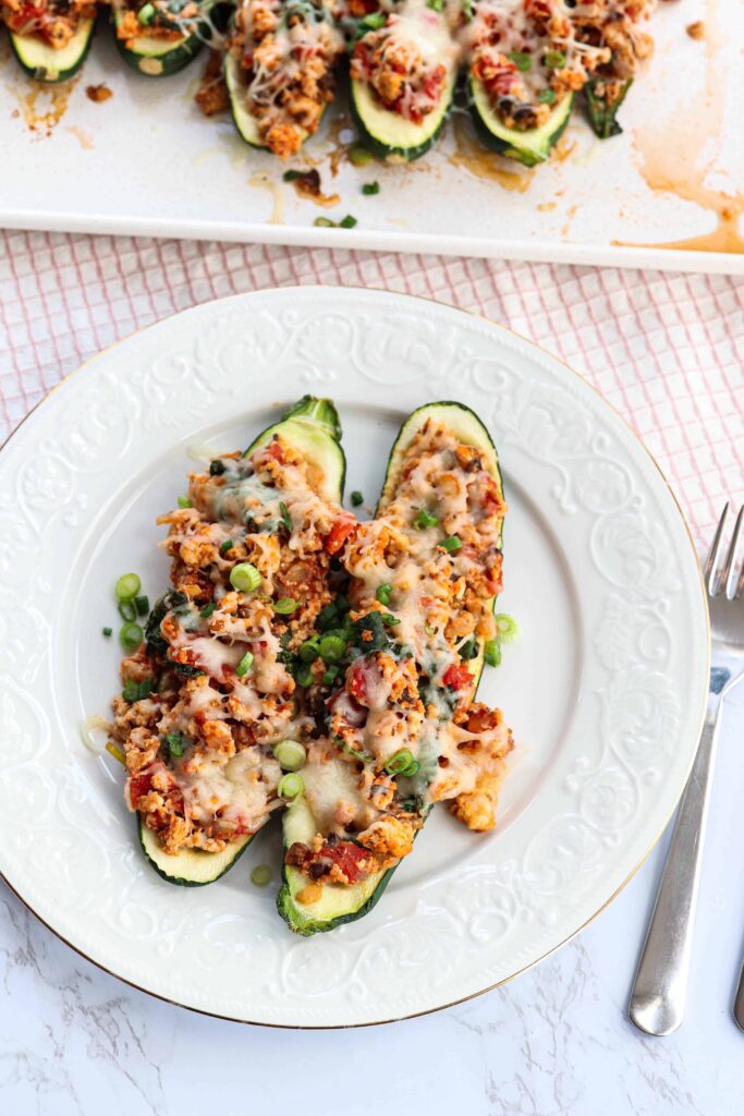 two stuffed zucchini boats on a white plate.