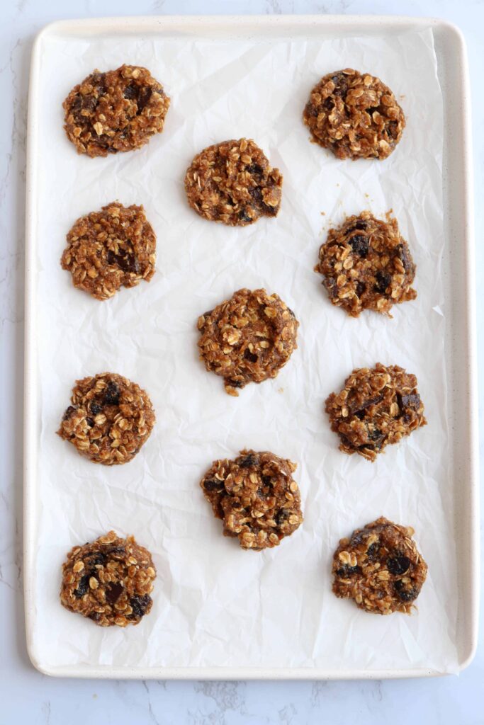 raw banana oatmeal cookies with chocolate chips on a paper lined baking sheet.