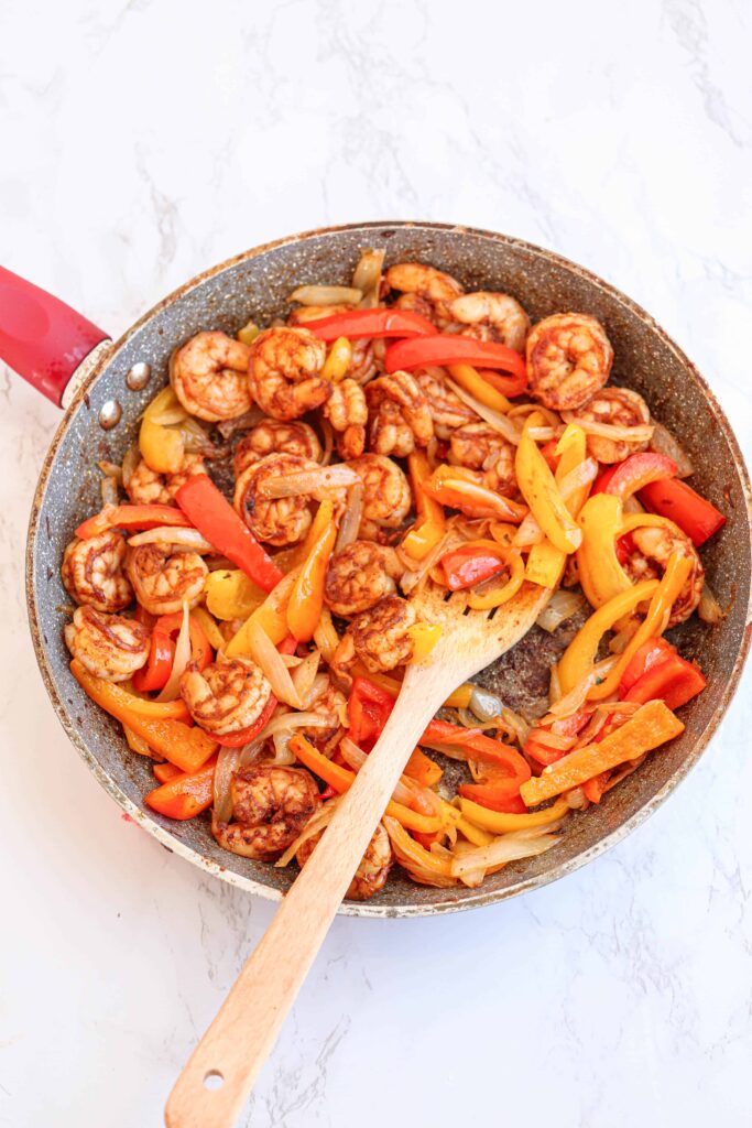 a skillet with shrimp, peppers and onions, cooked
