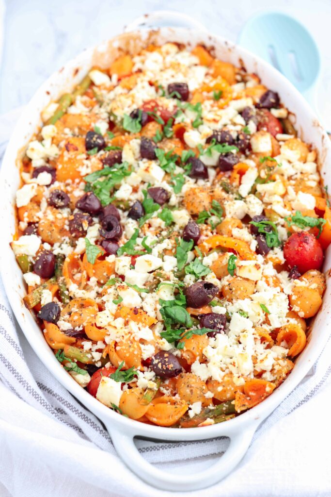 Greek chickpea pasta bake with olives and feta cheese in an oval casserole dish.