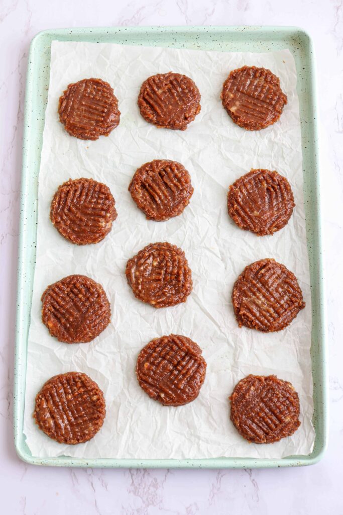 12 raw flourless peanut butter banana cookies flattened on a baking sheet