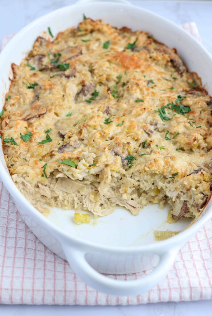 creamy chicken and mushroom cauliflower rice casserole in a white oval dish with some casserole taken out
