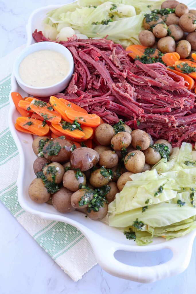 a white tray with shredded corned beef, baby potatoes, carrots, onions and cabbage 