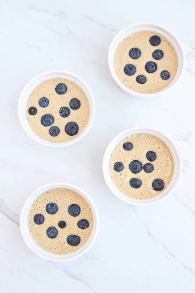 four ramekins with batter and blueberries before baking