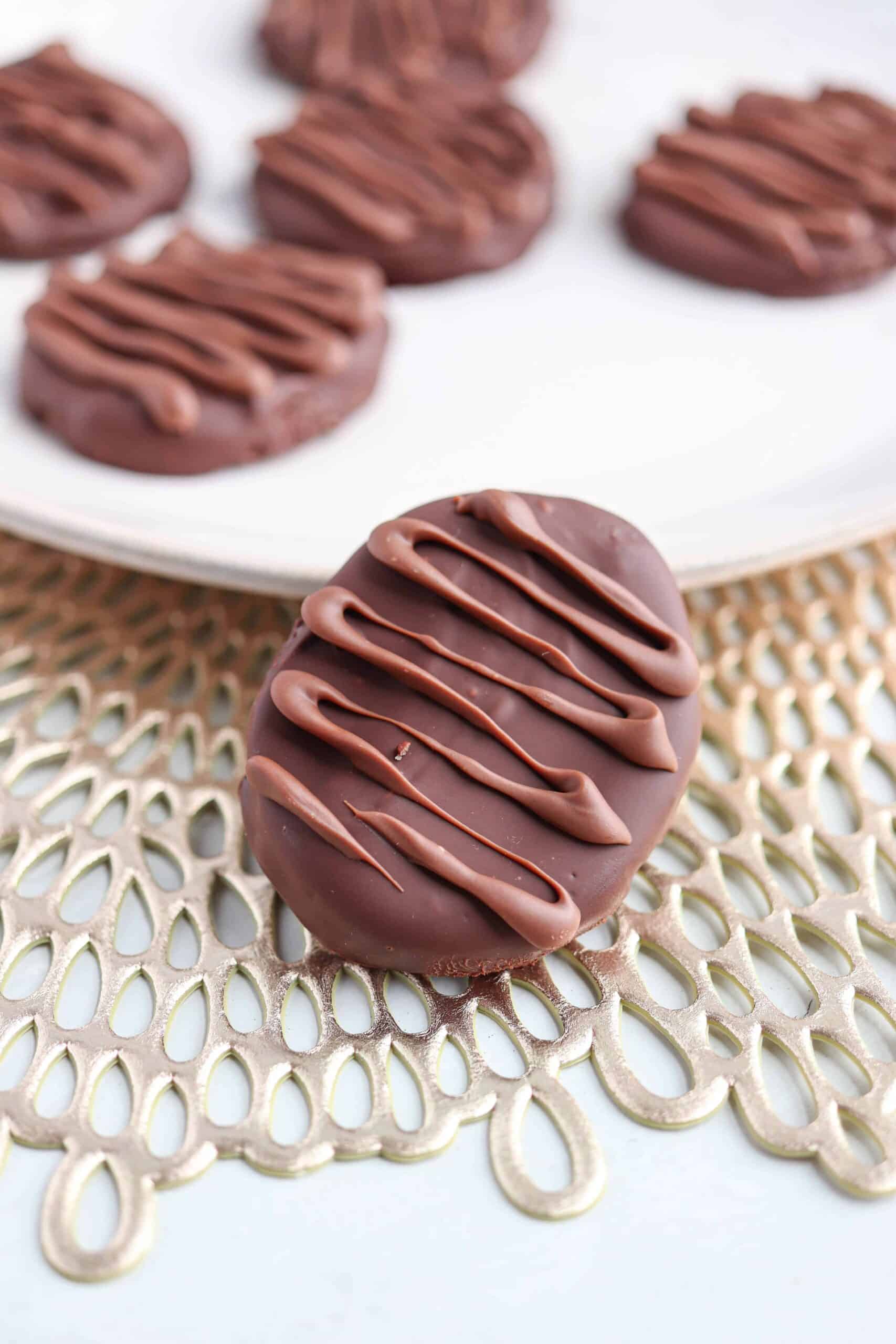 peanut butter egg in chocolate closeup with more eggs on a white plate in the background