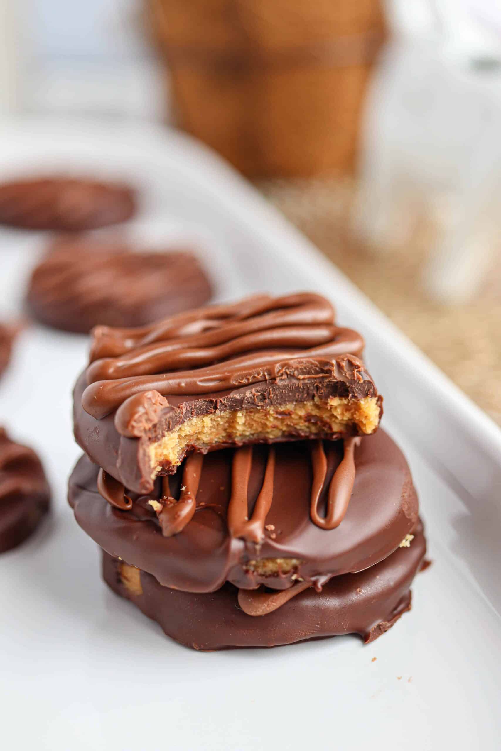 chocolate dipped peanut butter eggs in a stack with the top egg bitten to show the filling