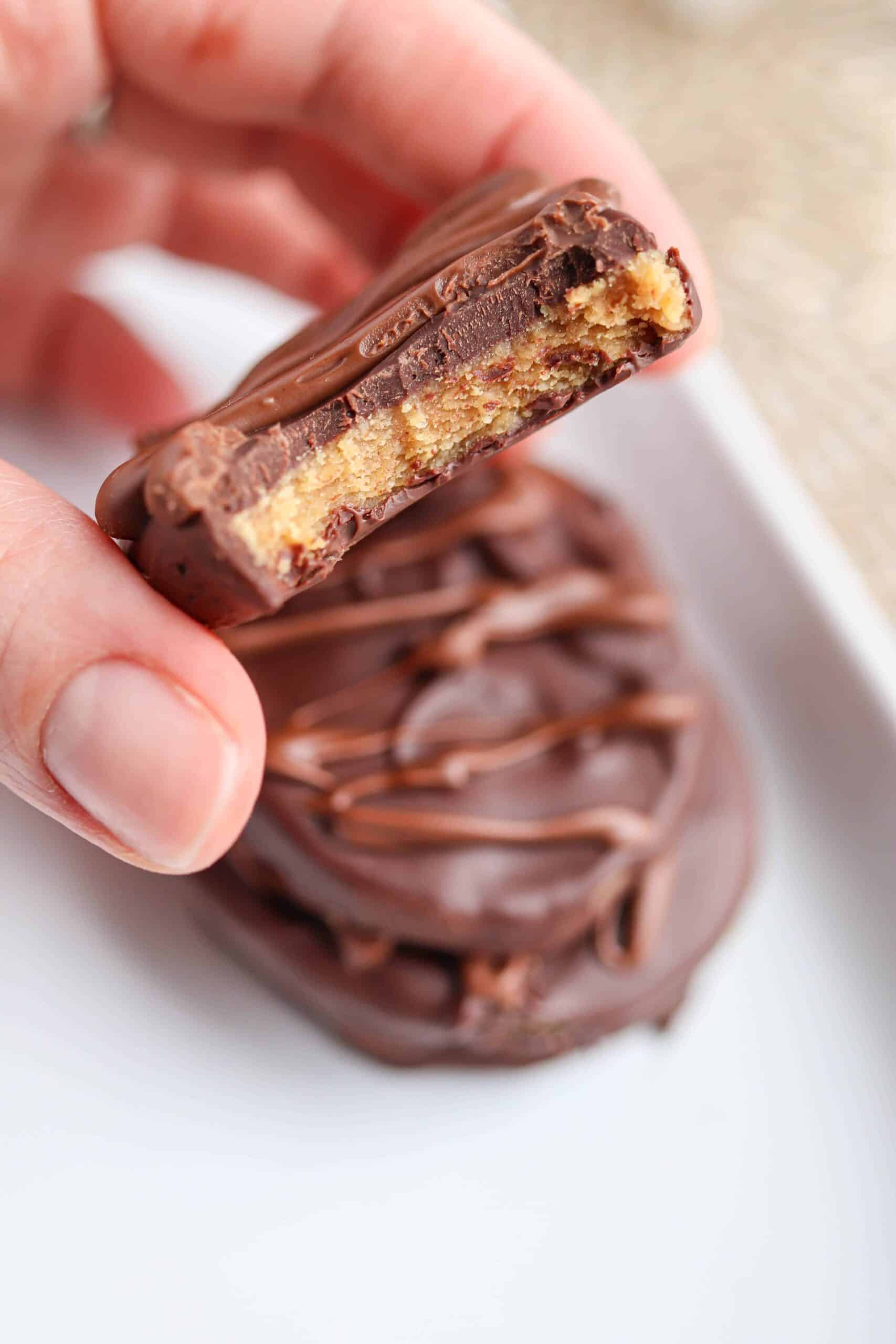 peanut butter chocolate eggs on a white plate and one egg bitten to show peanut butter filling 
