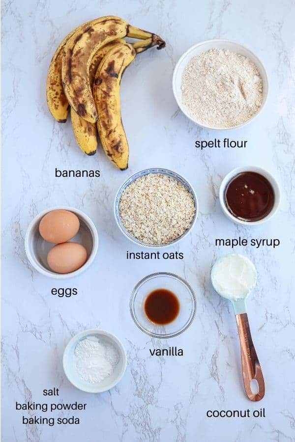 ingredients for making banana bread on marble surface with captions.