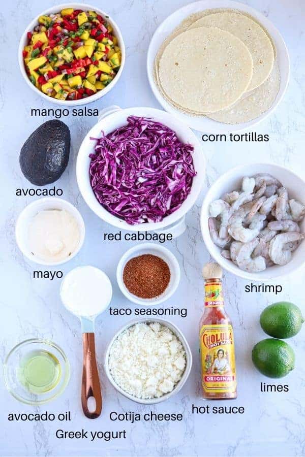 shrimp tacos ingredients laid out on white marble surface