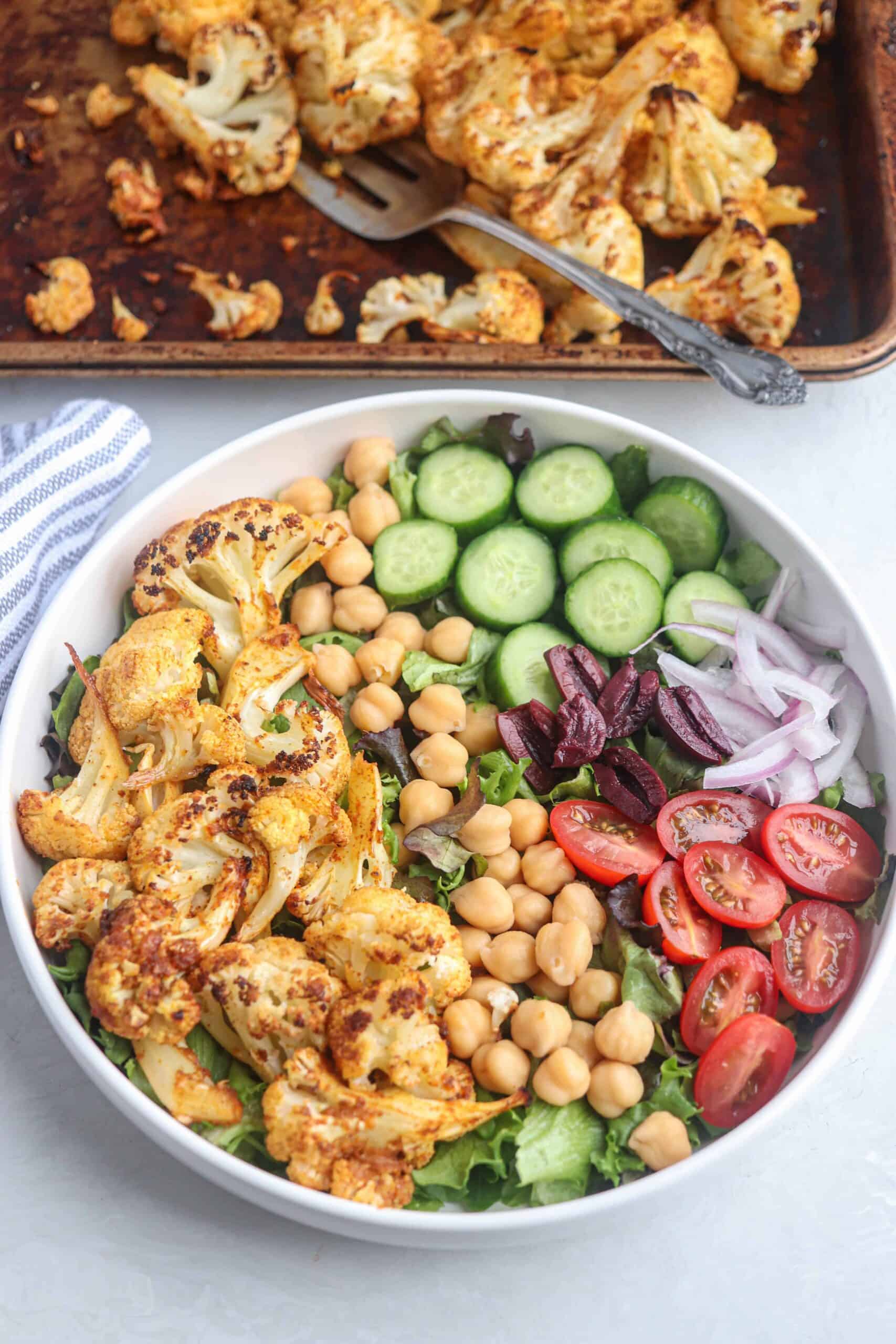 cauliflower shawarma bowl in a white bowl with veggies and chickpeas.