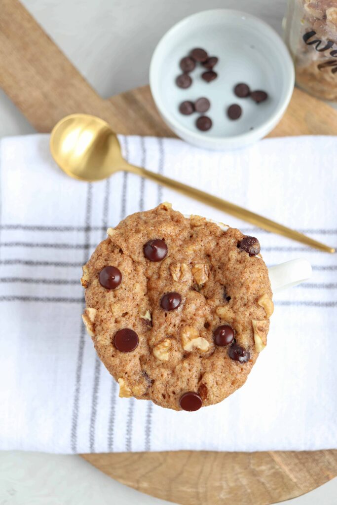 banana mug cake topped with walnuts and chocolate chips after cooking.