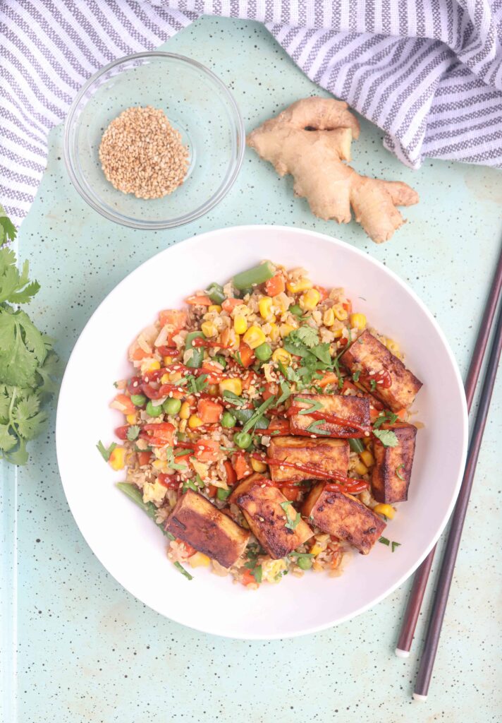 tofu cauliflower fried rice with veggies in a white bowl.