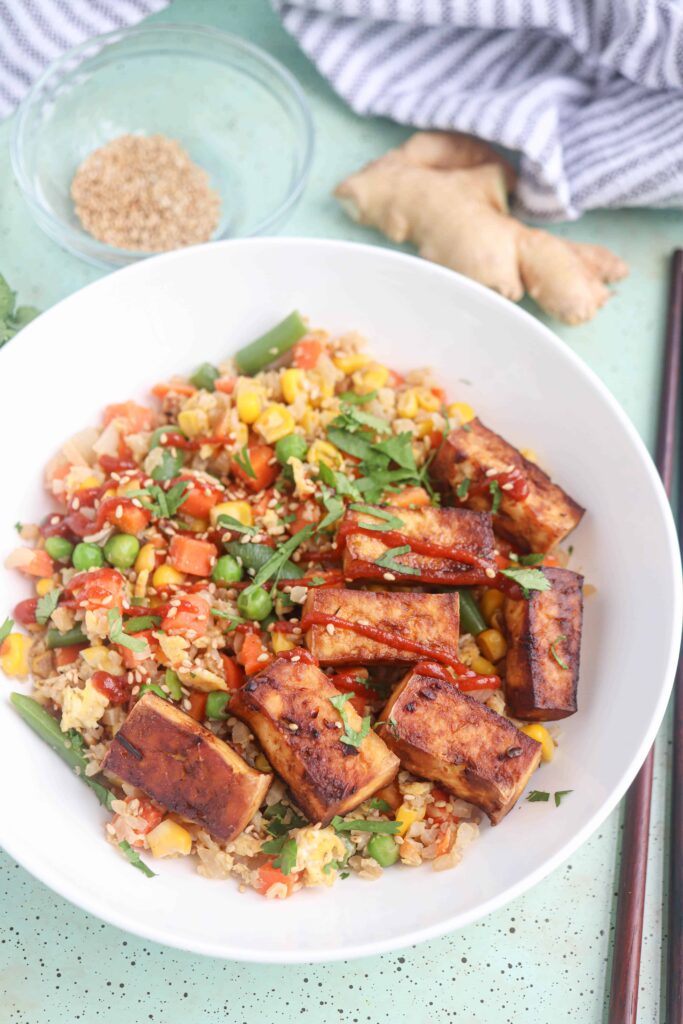 tofu cauliflower fried rice with veggies in a white bowl.