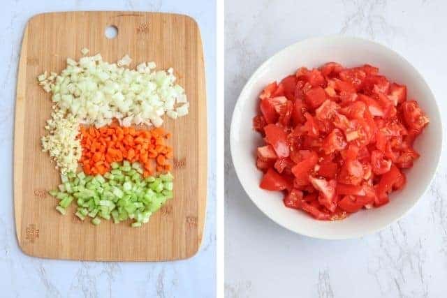 a wooden board with chopped onions, garlic, carrots and celery, and a white bowl with chopped fresh tomatoes.