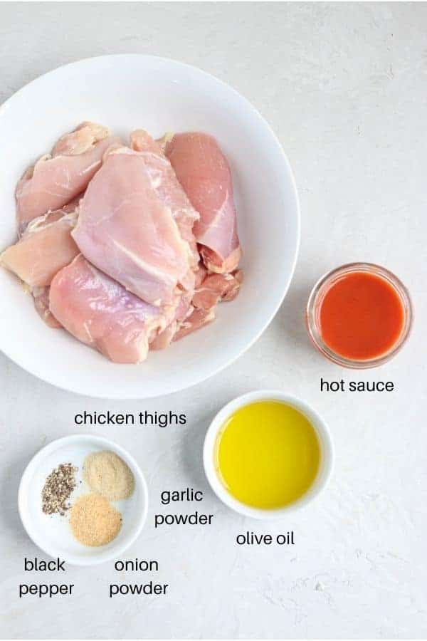 buffalo chicken thighs ingredients laid out on a light gray surface and labeled.