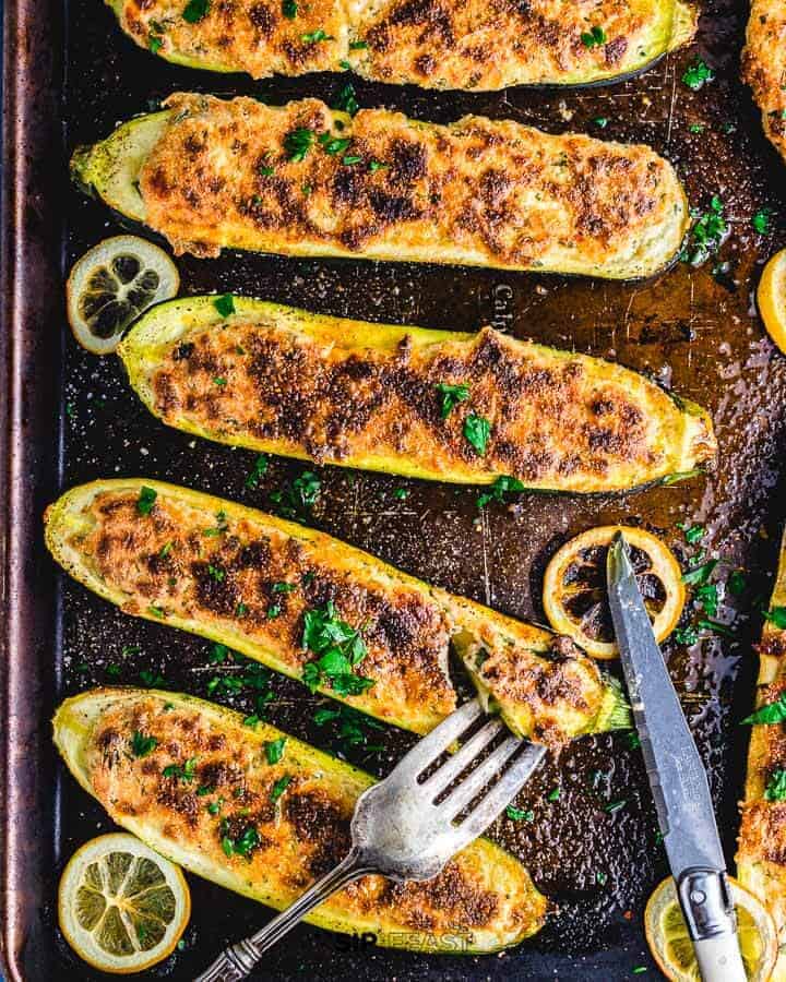 zucchini boats stuffed with ricotta cheese on a baking tray.