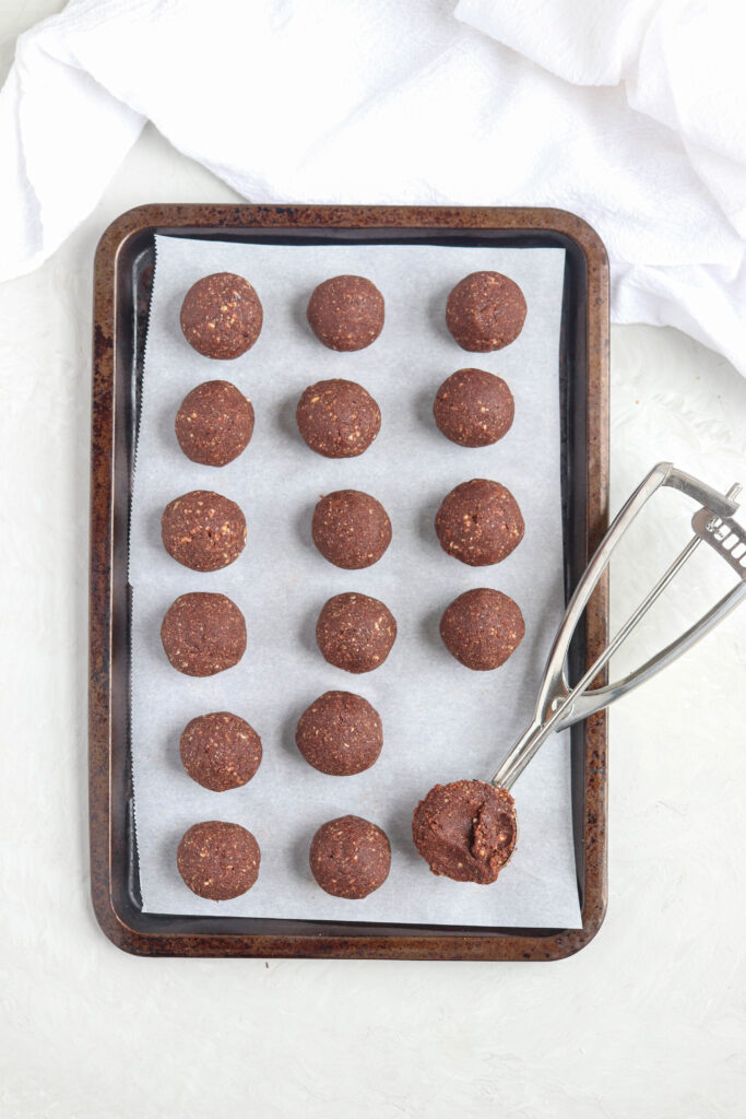 chocolate bliss balls on paper lined cookie sheet.