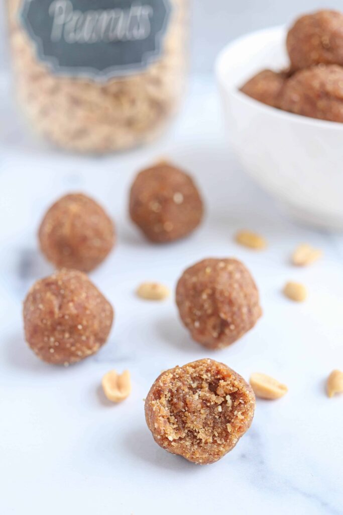 peanut butter balls on a white marble surface, bite shot.