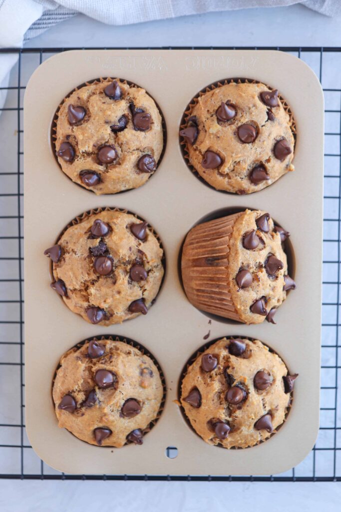 six sweet potato chocolate chip muffins in a muffin tin.
