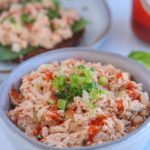tuna buffalo salad in a gray bowl drizzled with hot sauce and sprinkled with chives pin with a title on top