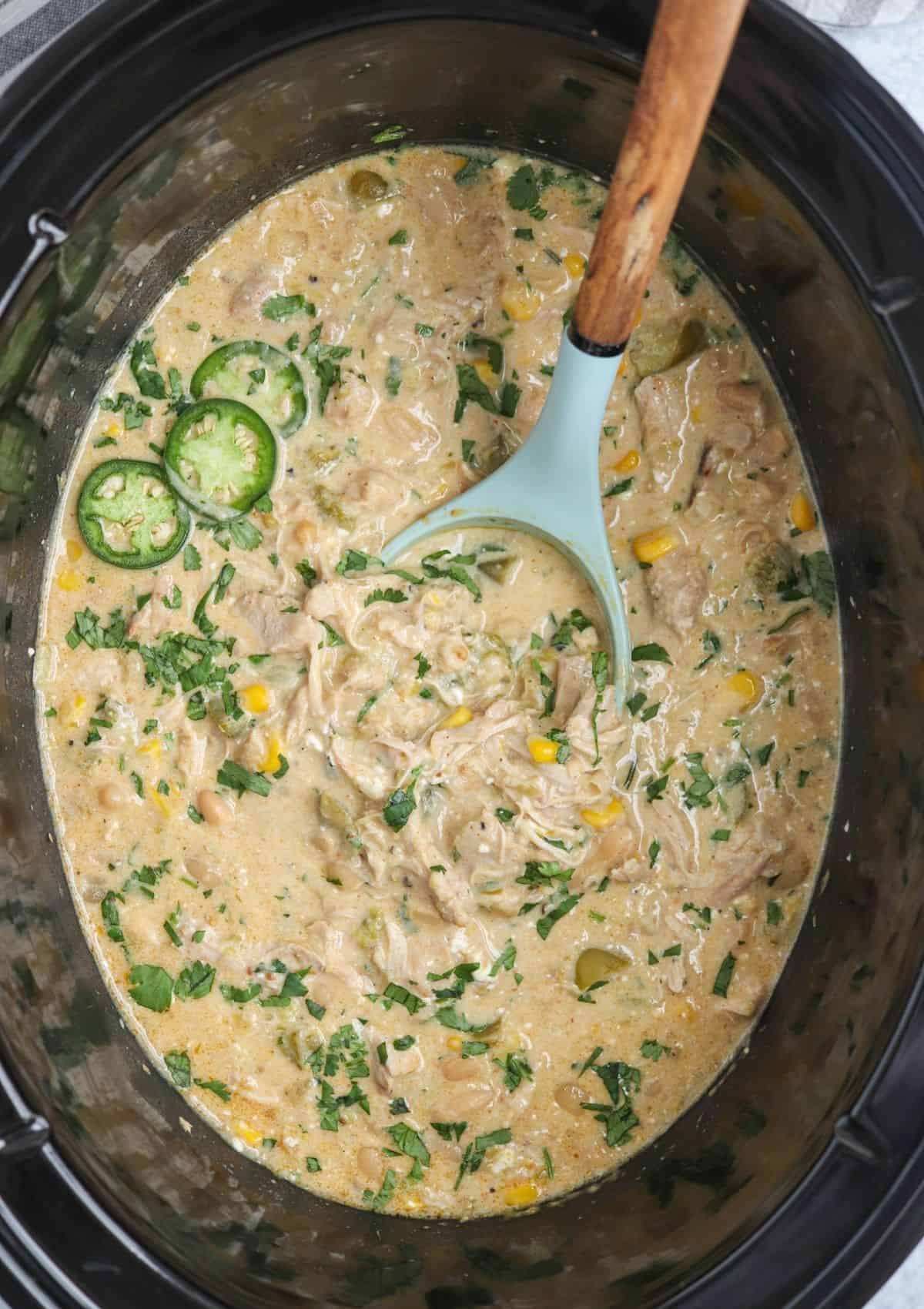 green chicken chili in a black slow cooker.