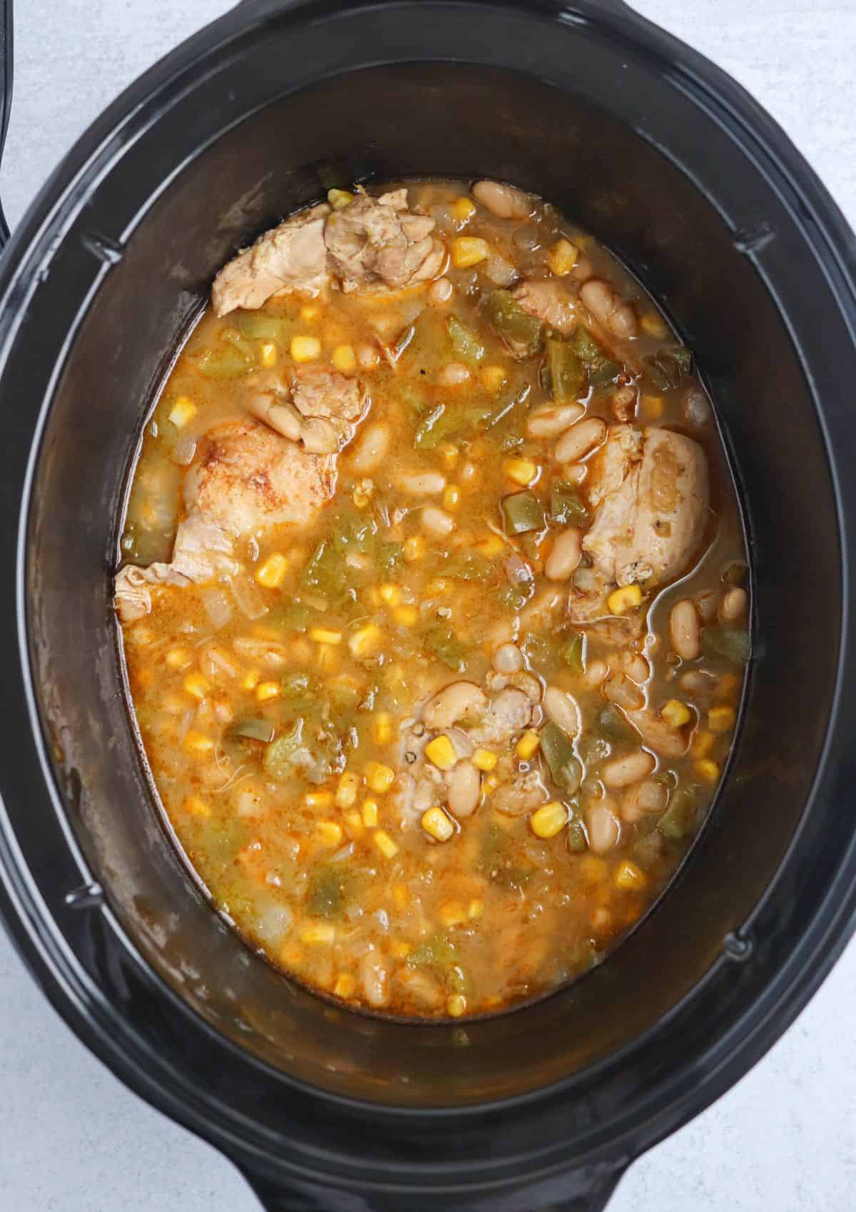 making green chicken chili in a black slow cooker.