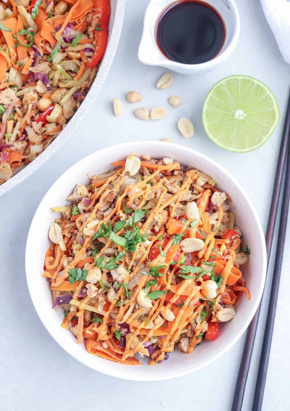 vegan egg roll in a bowl with tofu drizzled with spicy peanut sauce sprinkled with peanuts and chopped cilantro.