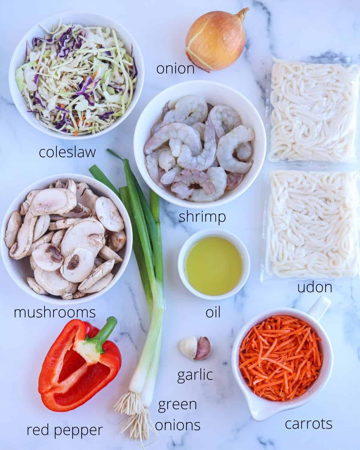 shrimp yaki udon ingredients on white marble surface with captions.