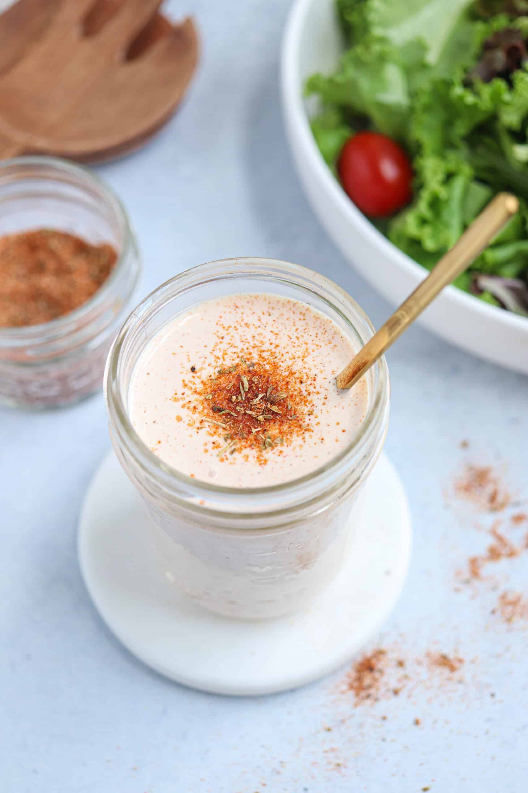creamy cajun salad dressing in a glass jar with a gold soon inserted.