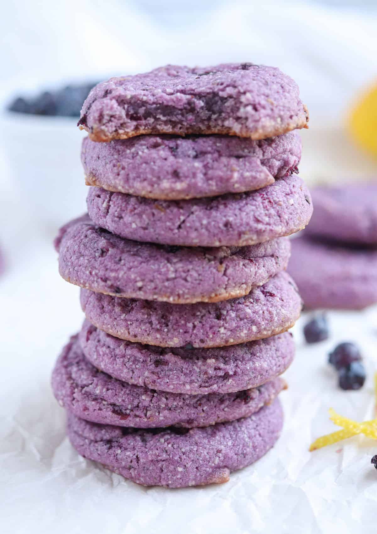 a stack of eight blueberry lemon cookies with the top cookie bitten into.