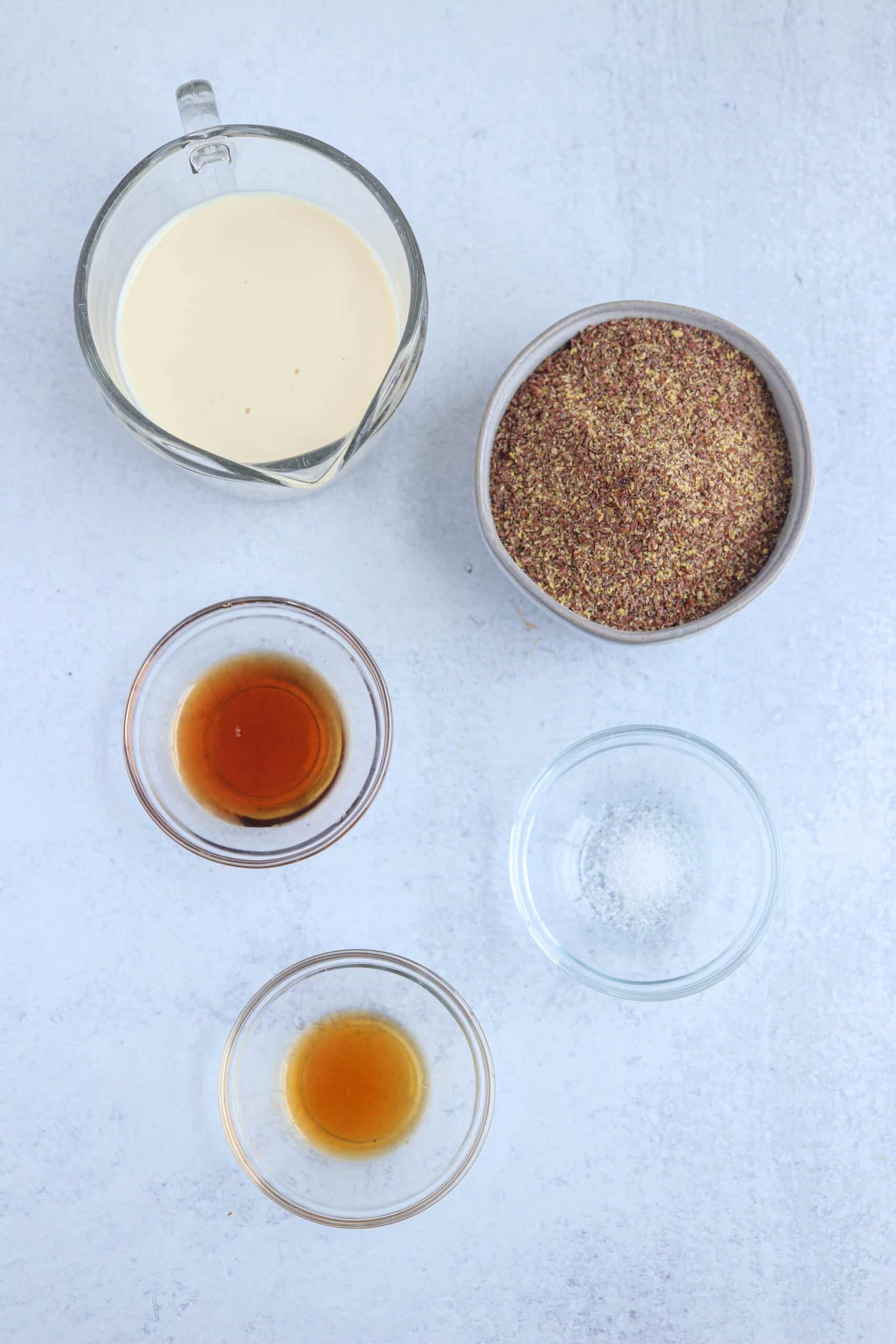 flaxseed pudding ingredients in round containers on light gray surface.