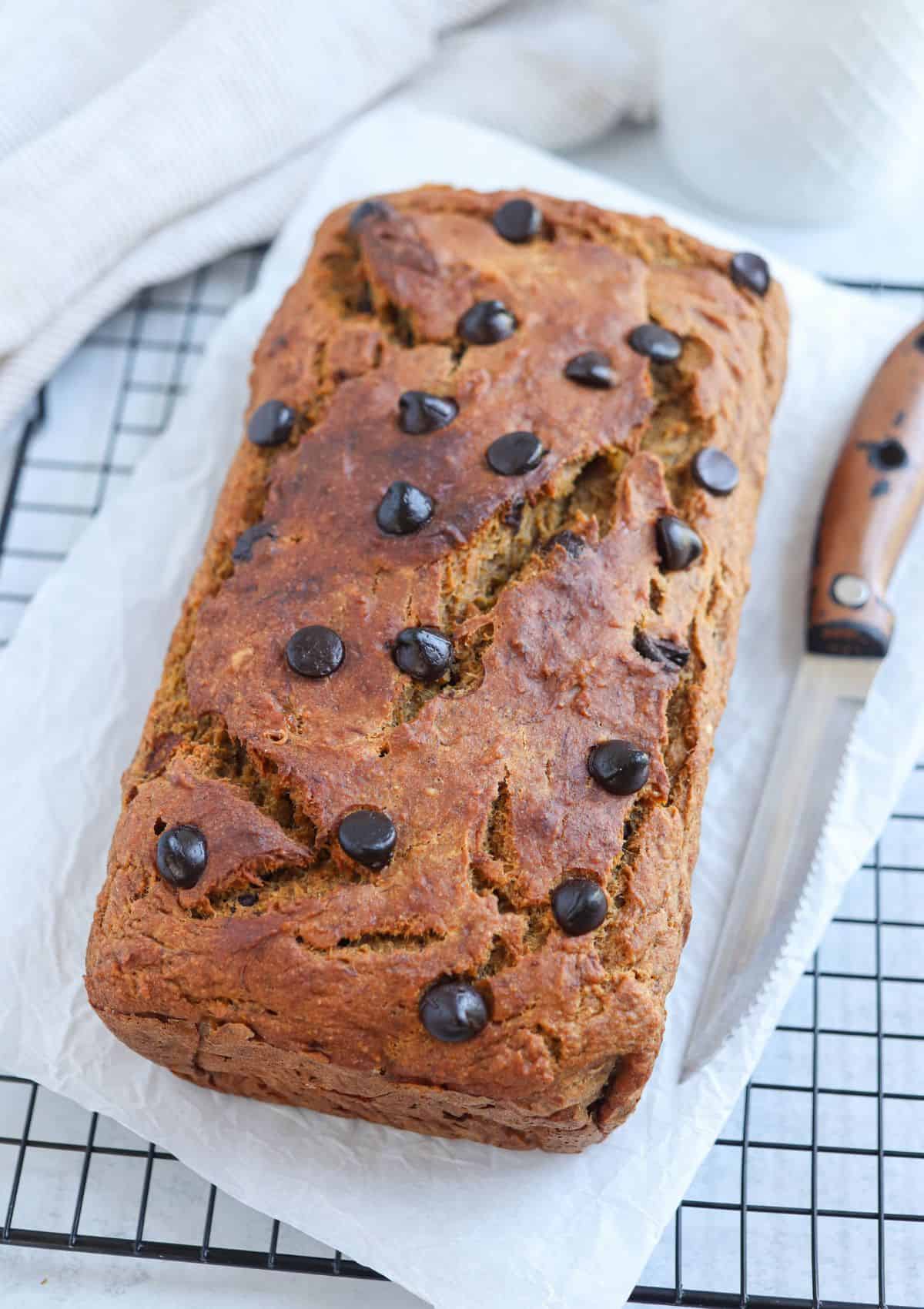 sweet potato banana bread with chocolate chips on parchment paper on a black wire rack.