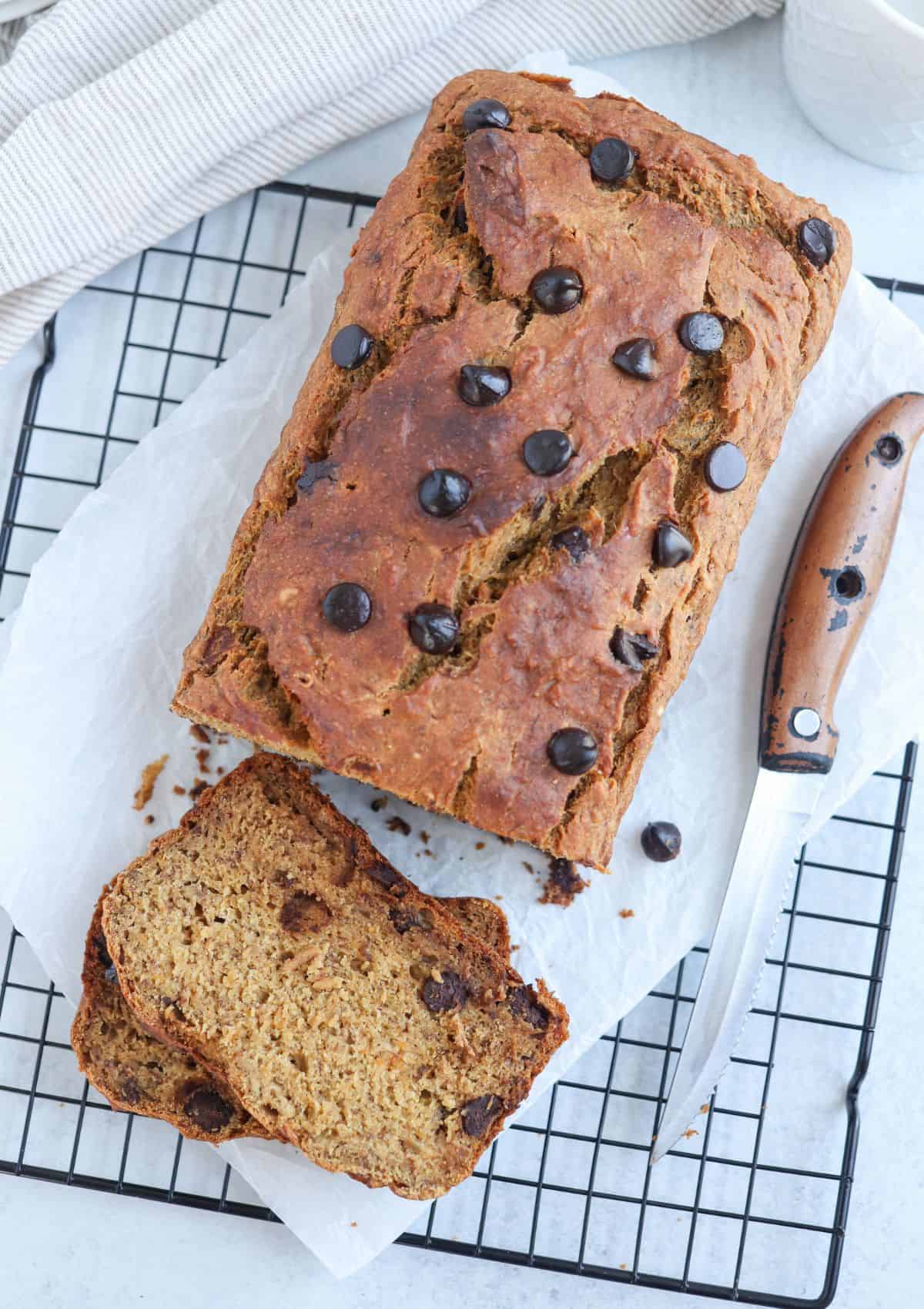 sweet potato banana bread with chocolate chips on parchment paper on a black wire rack
