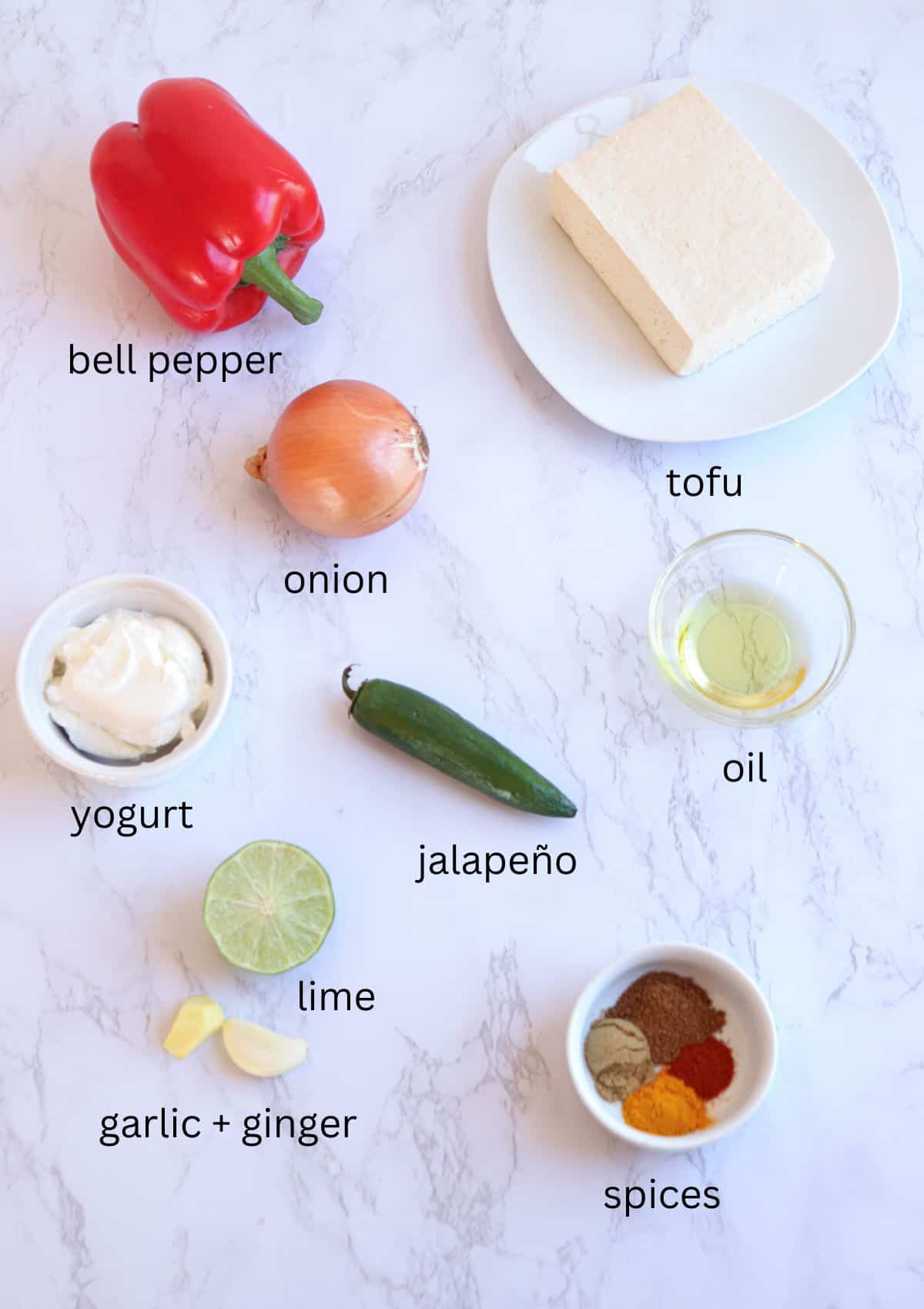 ingredients for making Indian tofu curry on white marble surface with captions.