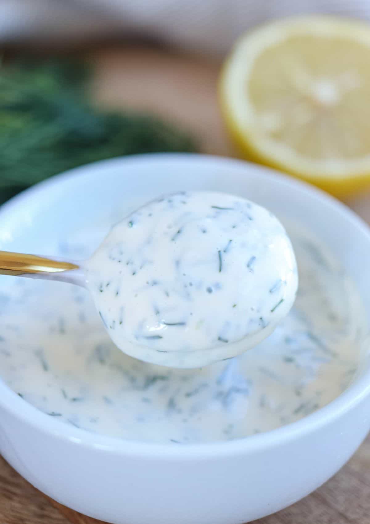 dill aioli on a golden spoon over a bowl with more aioli.