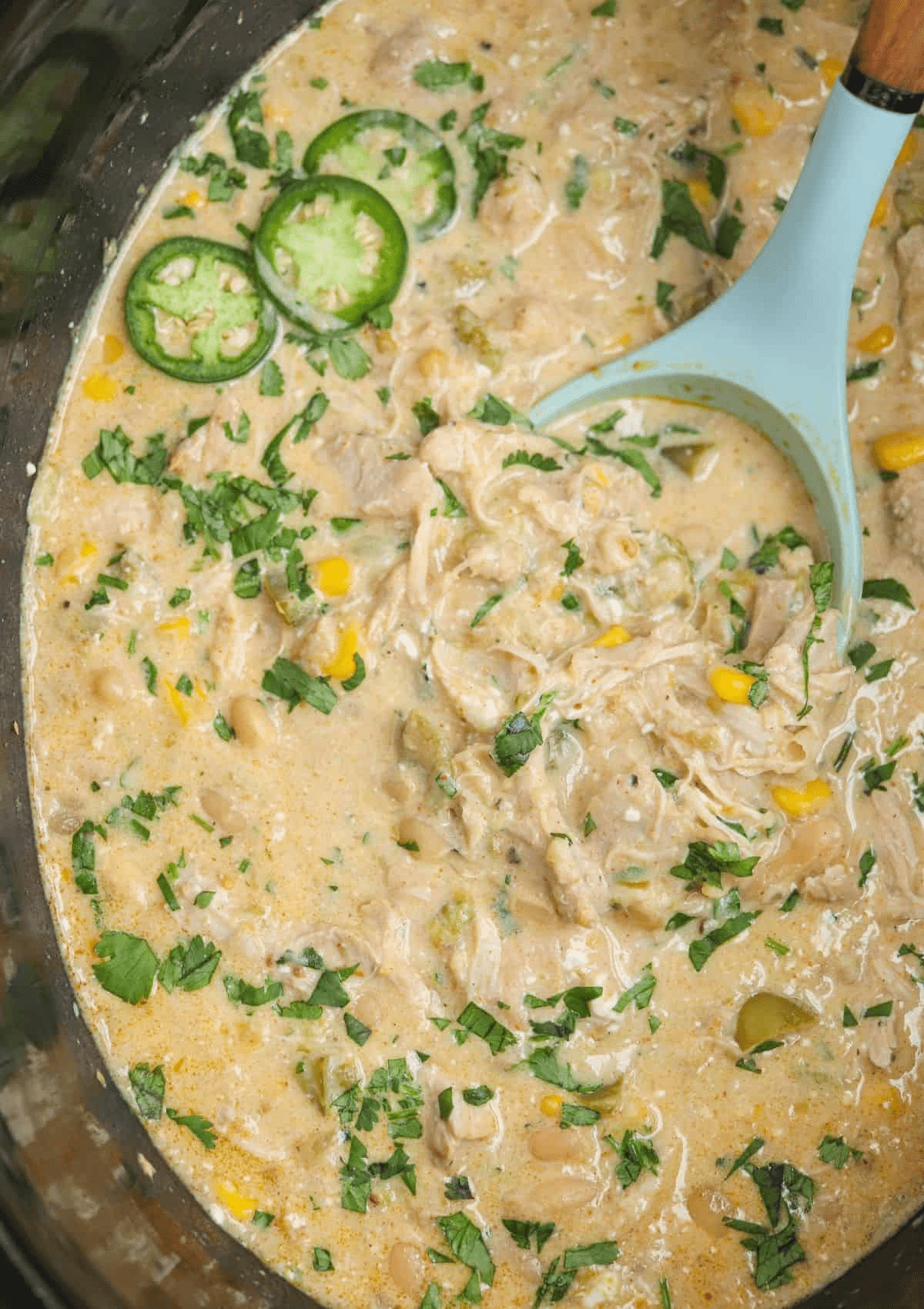 green chicken chili in a black crock pot.