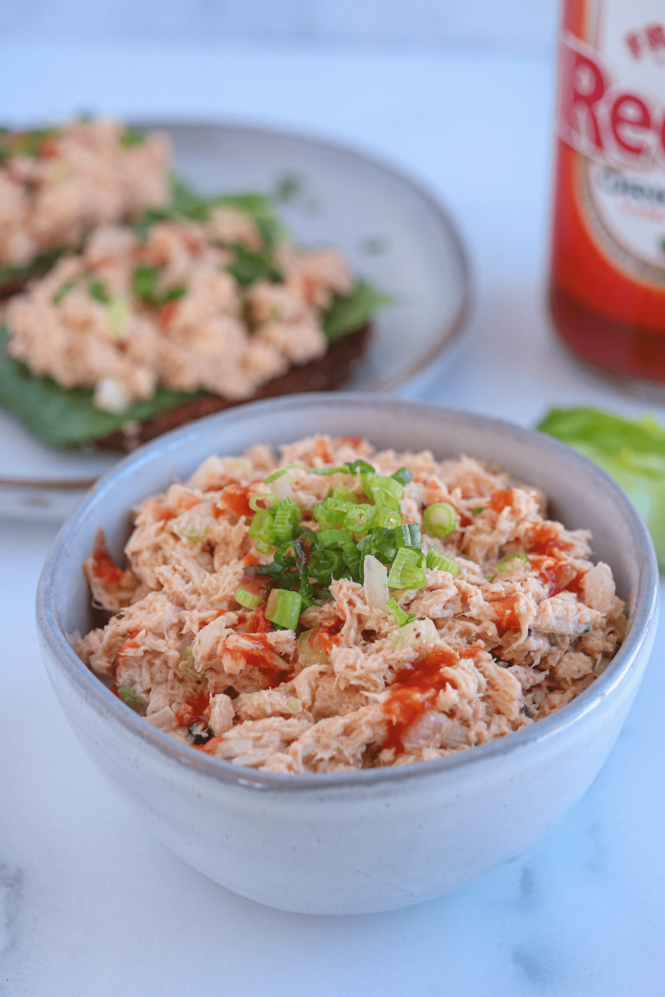 buffalo tuna salad in a small gray bowl sprinkled with sliced green onion.