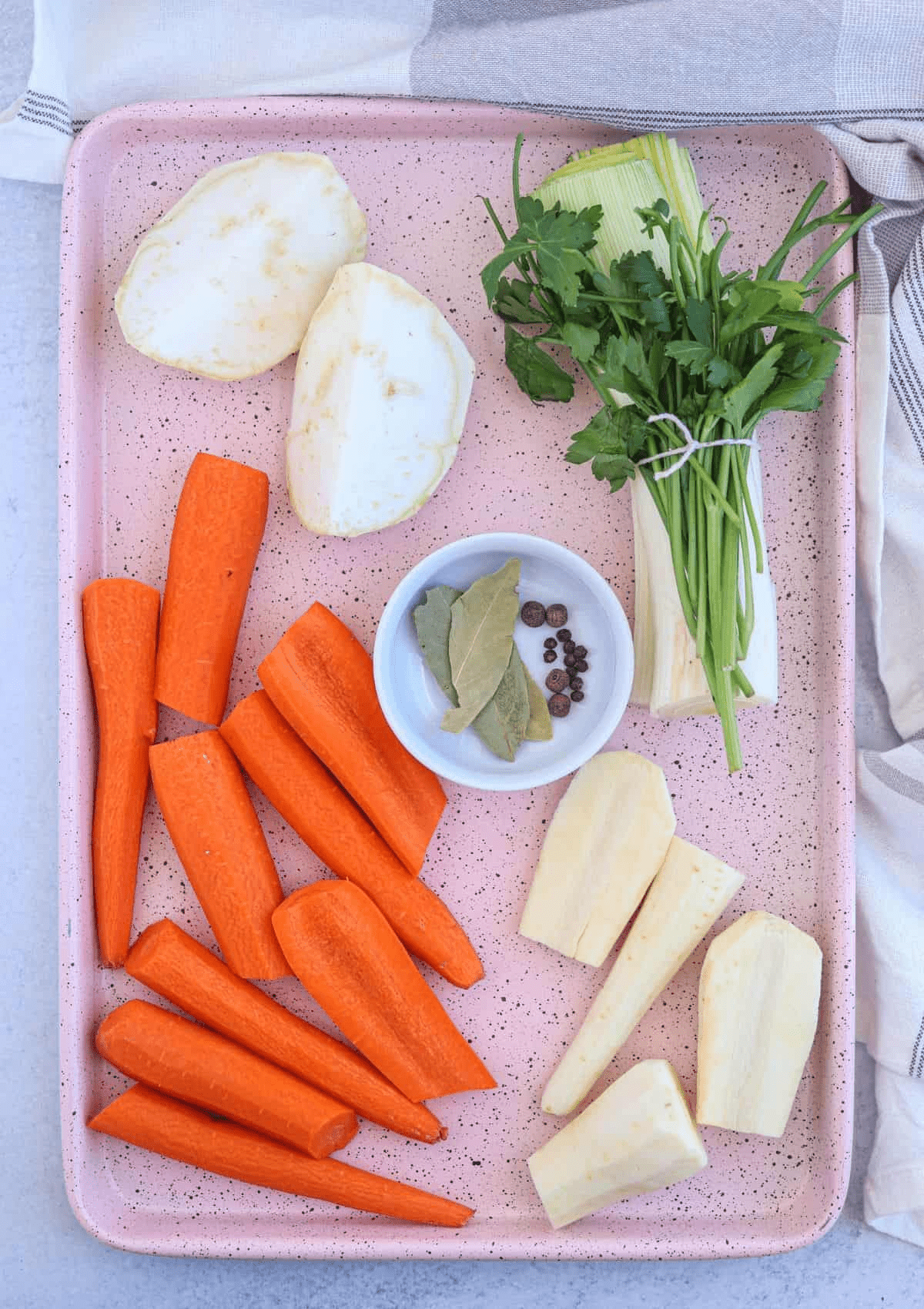 vegetables and spices on a pink baking tray.