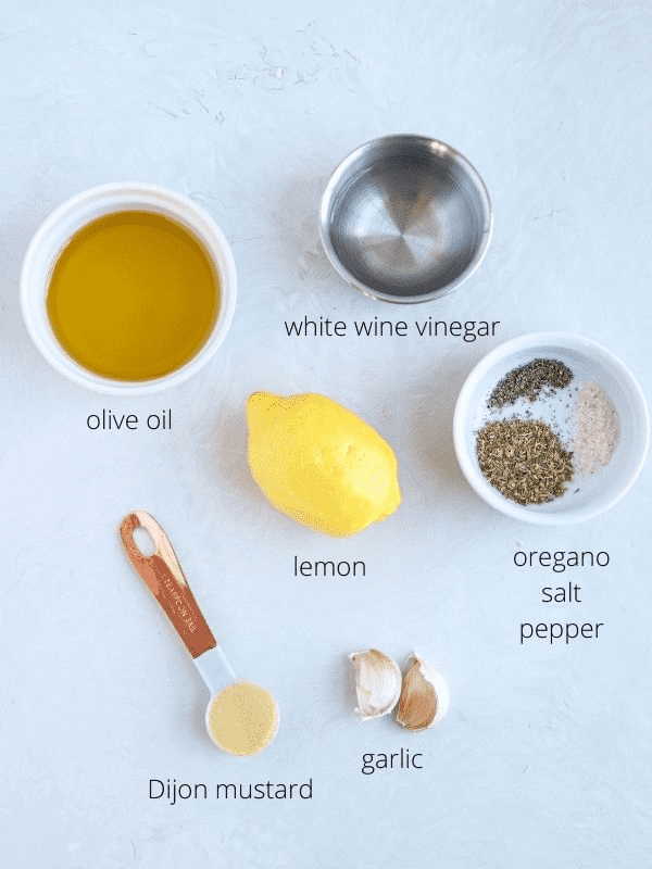 Greek salad dressing ingredients on light gray surface with captions.