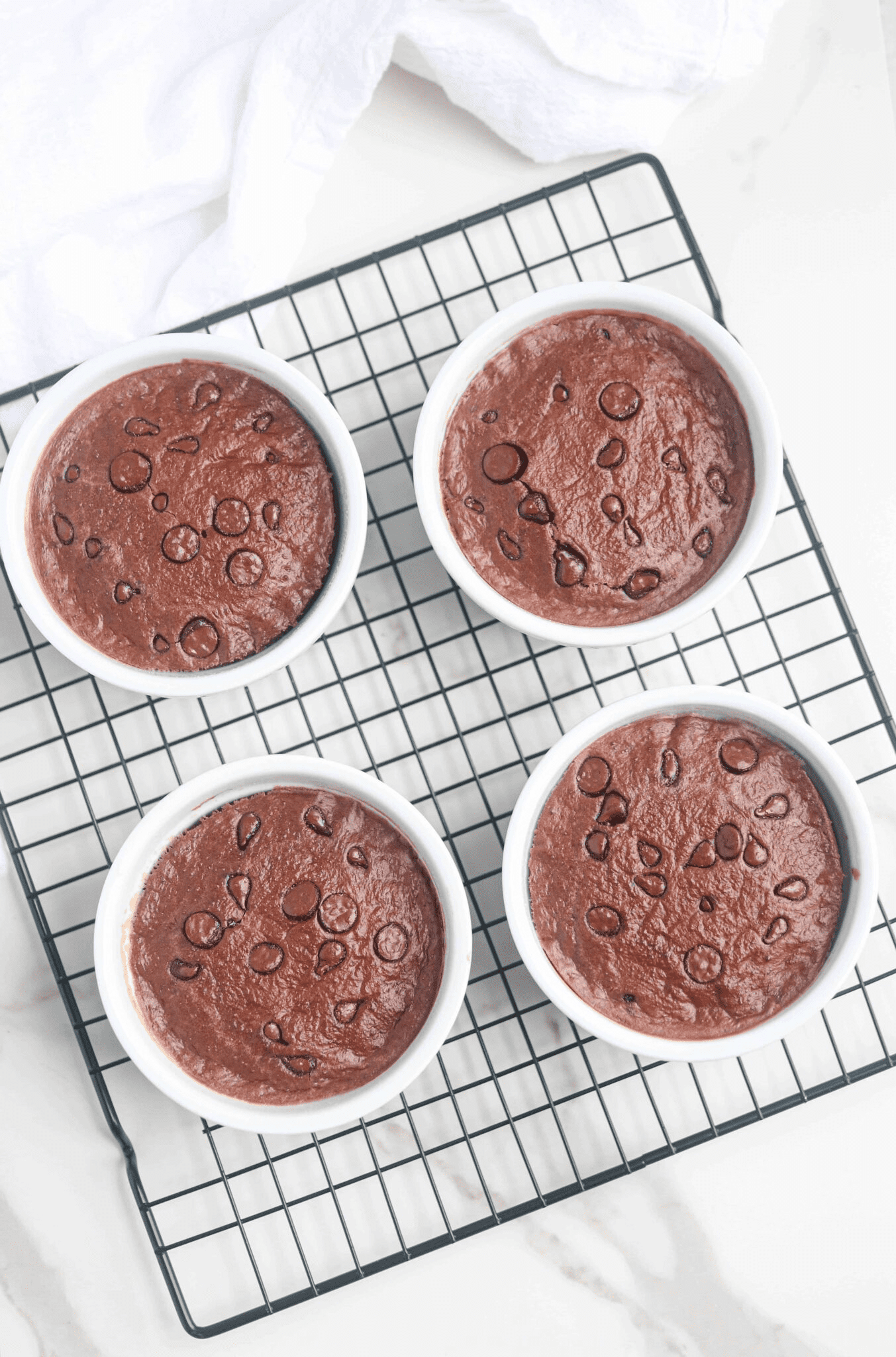 four ramekins with chocolate baked oats on a black cooling rack. 