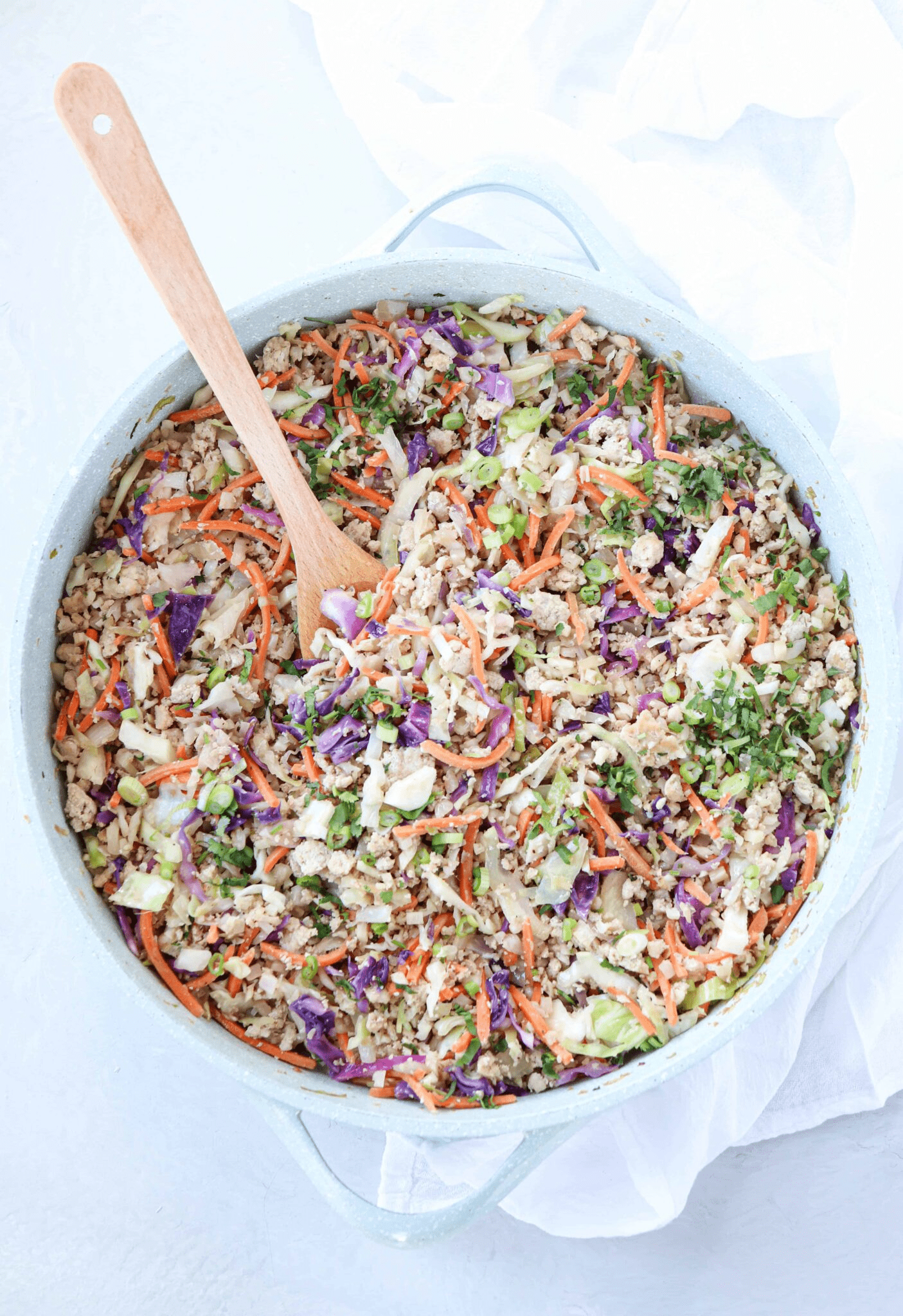 egg roll in a bowl dish in a large teal skillet. 
