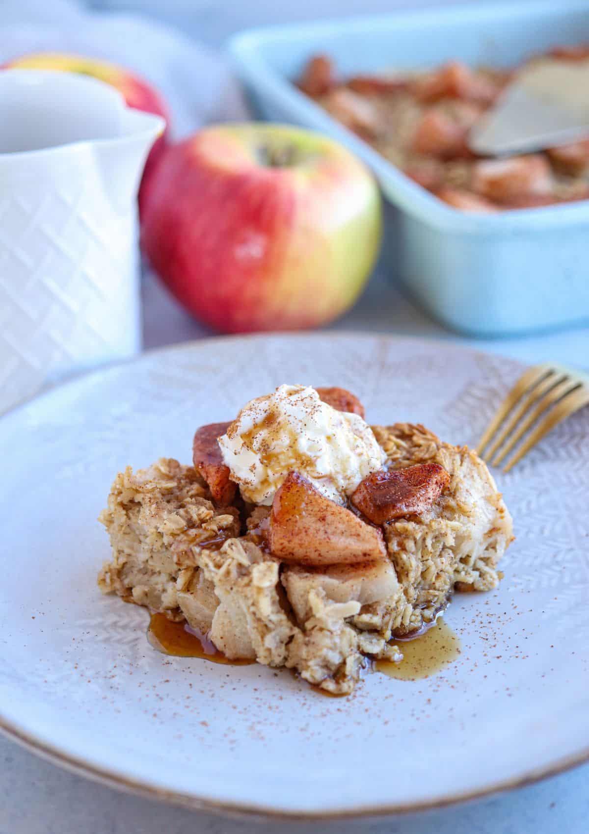 apple pie baked oatmeal square topped with cooked apples, whipped cream, cinnamon and maple syrup.