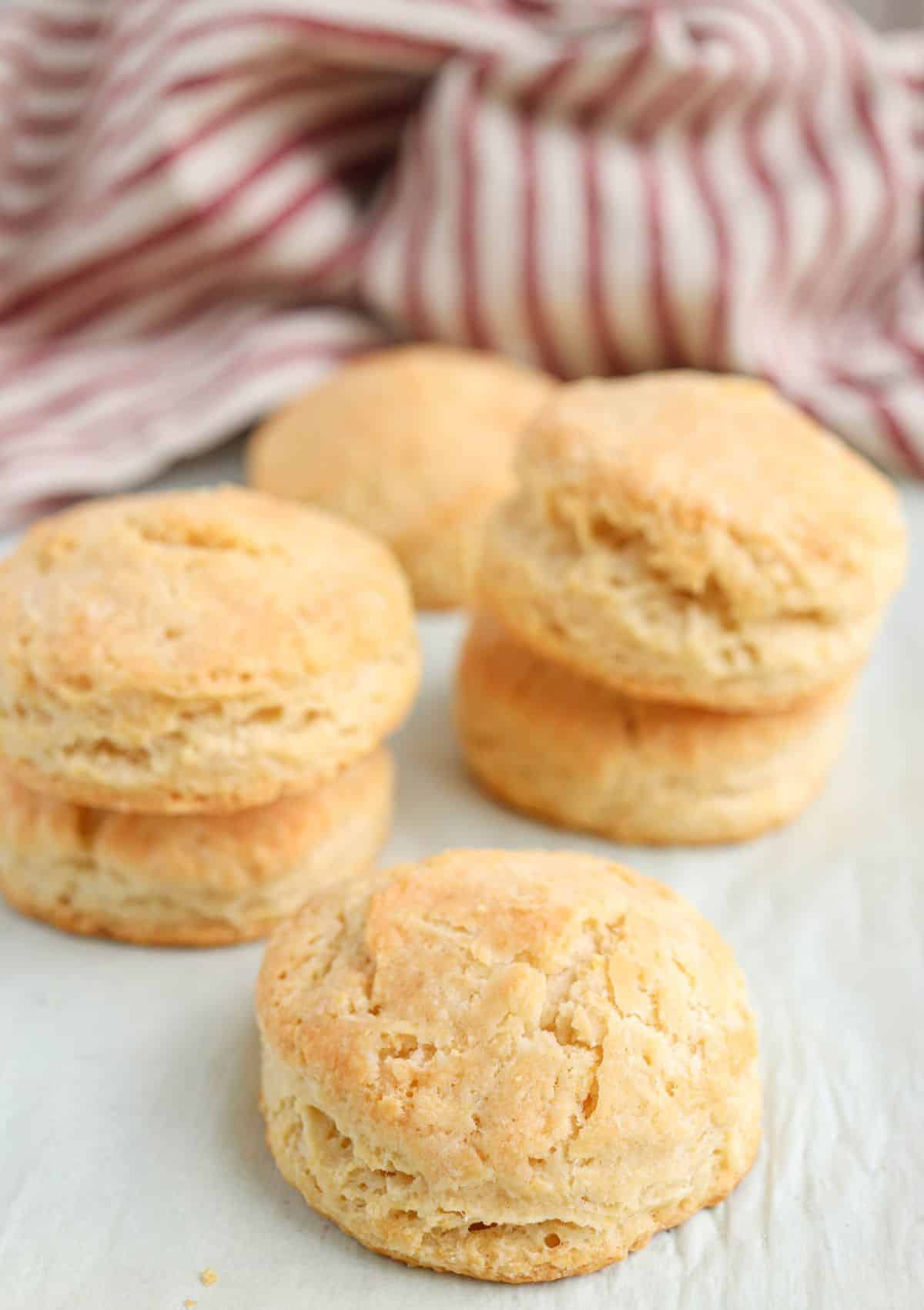 freshly baked round biscuits, stacked on parchment paper.
