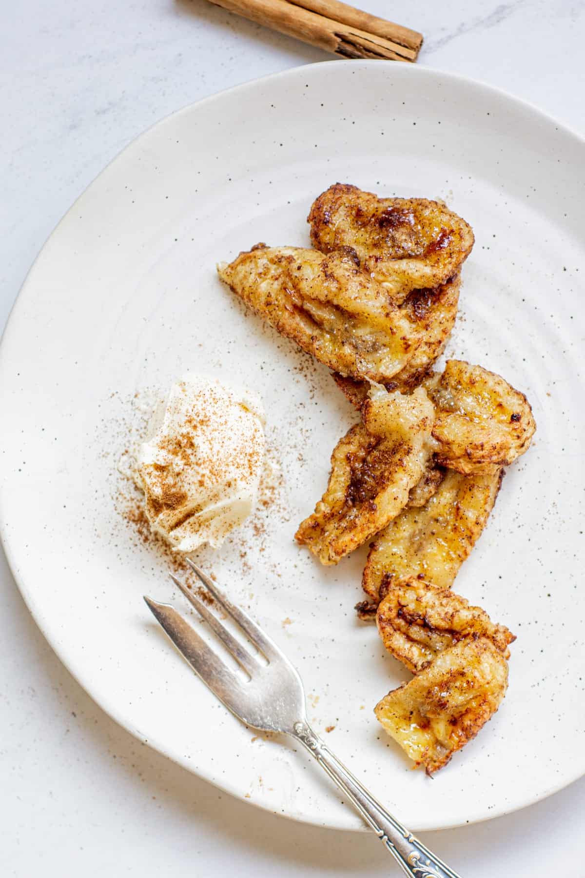 air fried banana chunks on a plate dusted with cinnamon.