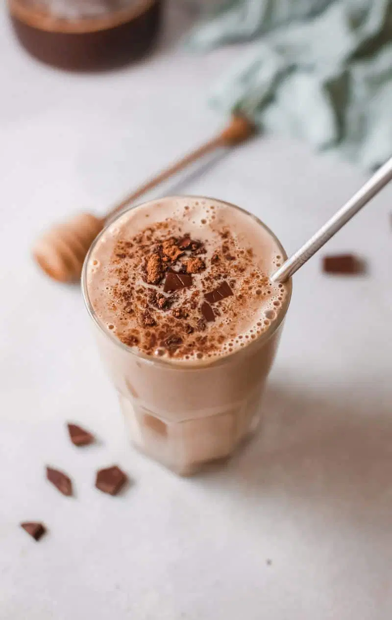 coffee banana smoothie in a tall glass with a silver straw.