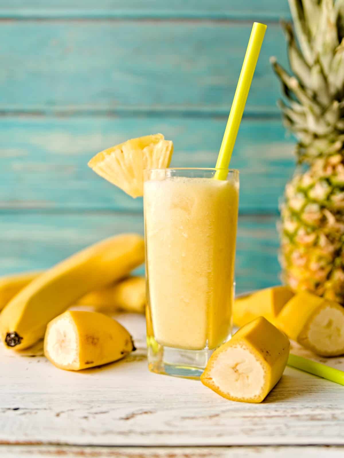 pineapple banana smoothie in a glass with a straw.