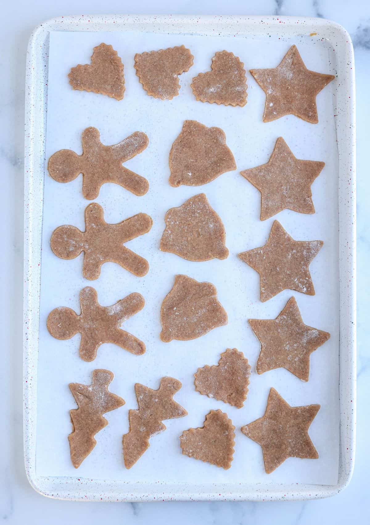 Polish gingrebread cookies on a white cookie sheet on parchment paper, before baking. 