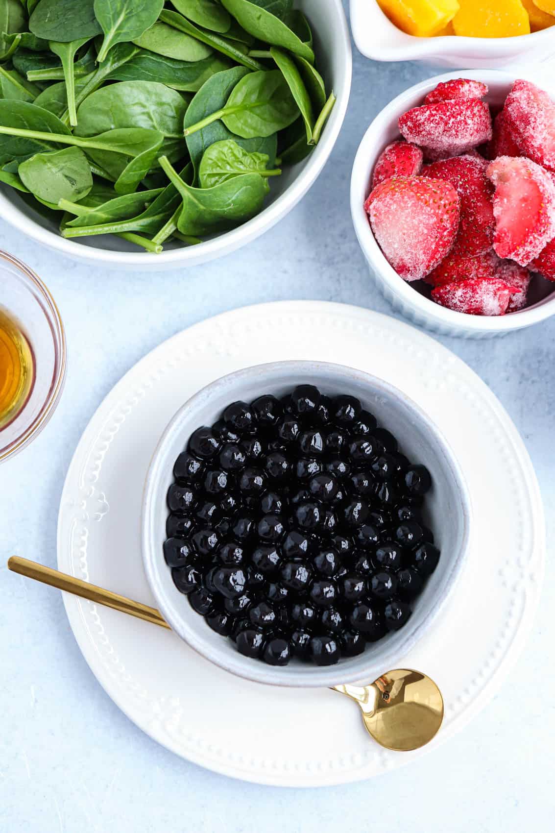 black boba pearls in a white ramekin on a white plate. 