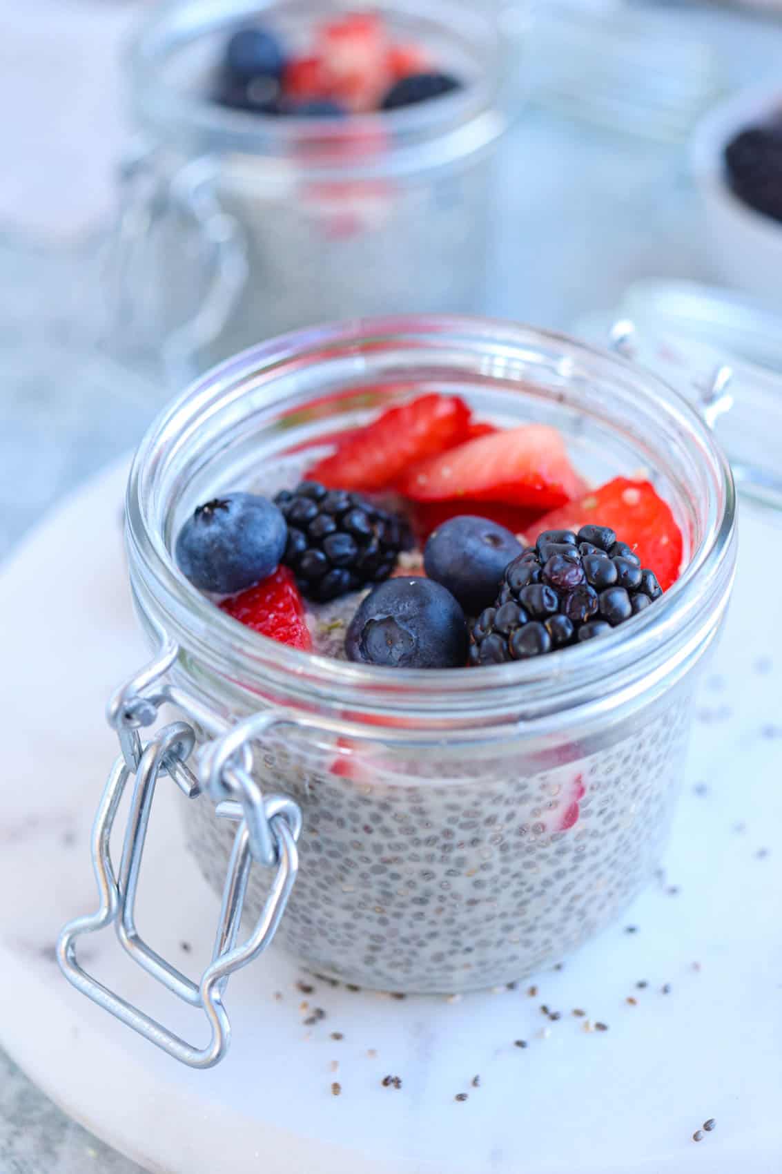 chia pudding topped with berries in a small mason jar.