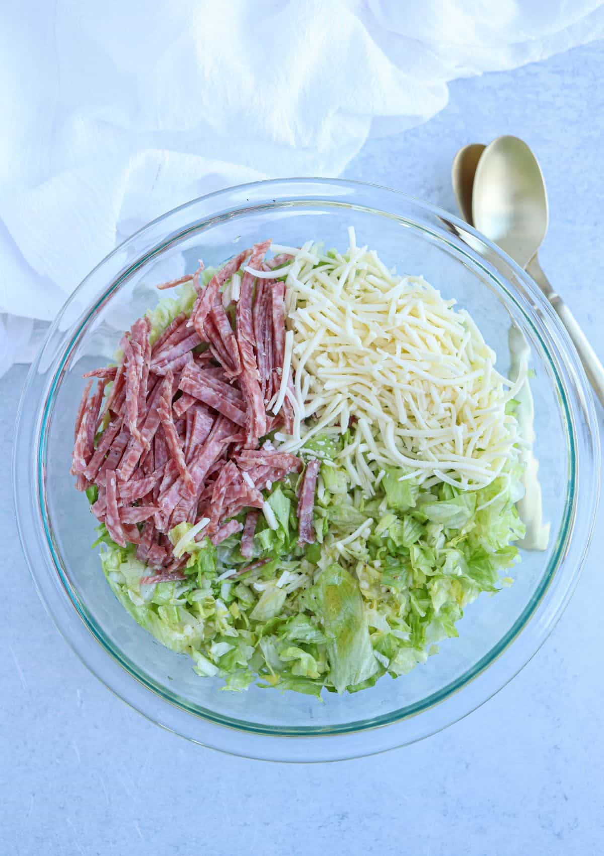 chopped salad with salami, mozzarella in a glass bowl, before mixing.
